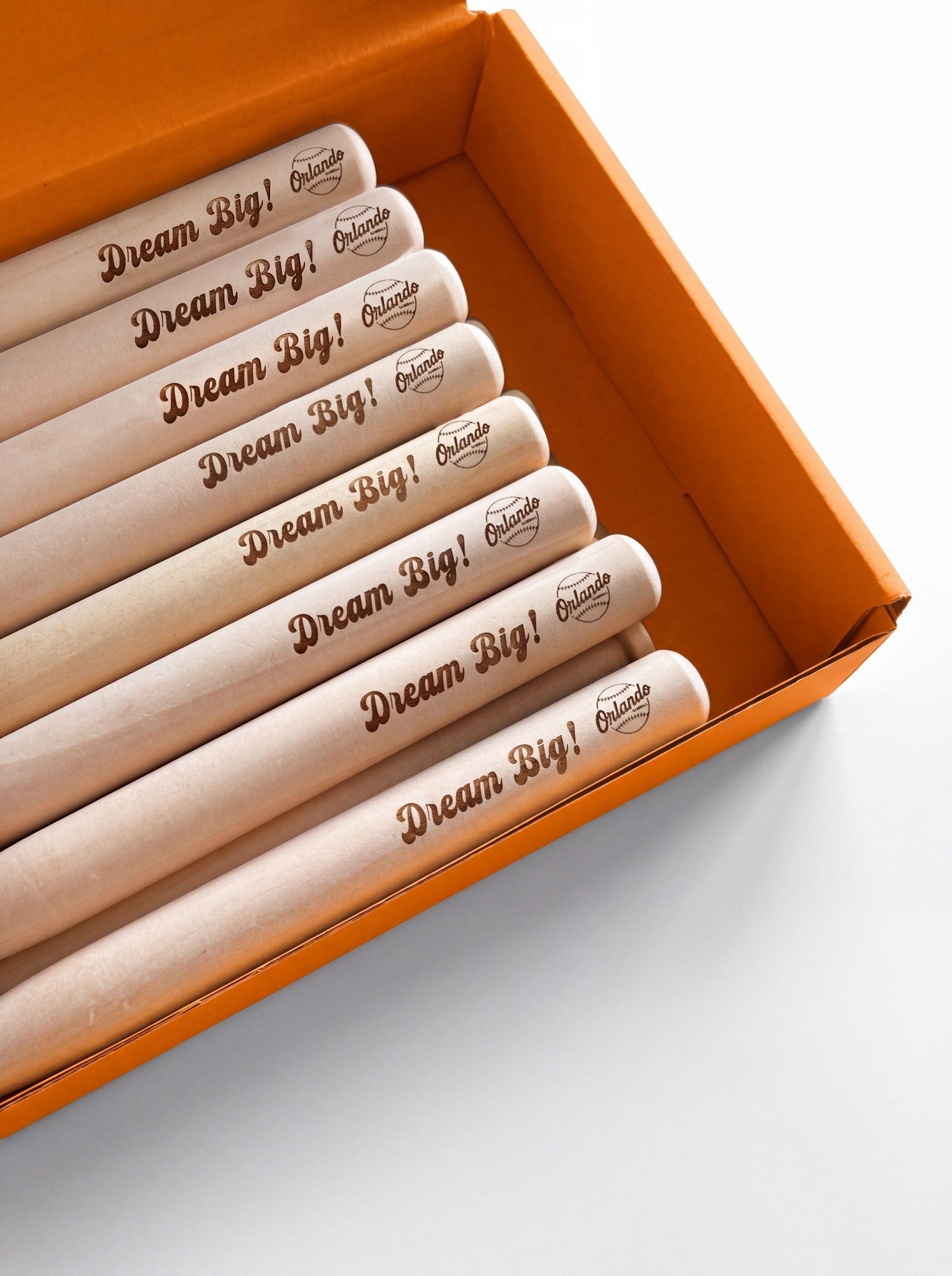 Engraved mini wooden baseball bats reading Dream Big with the Orlando Baseball logo, laid in an orange box.
